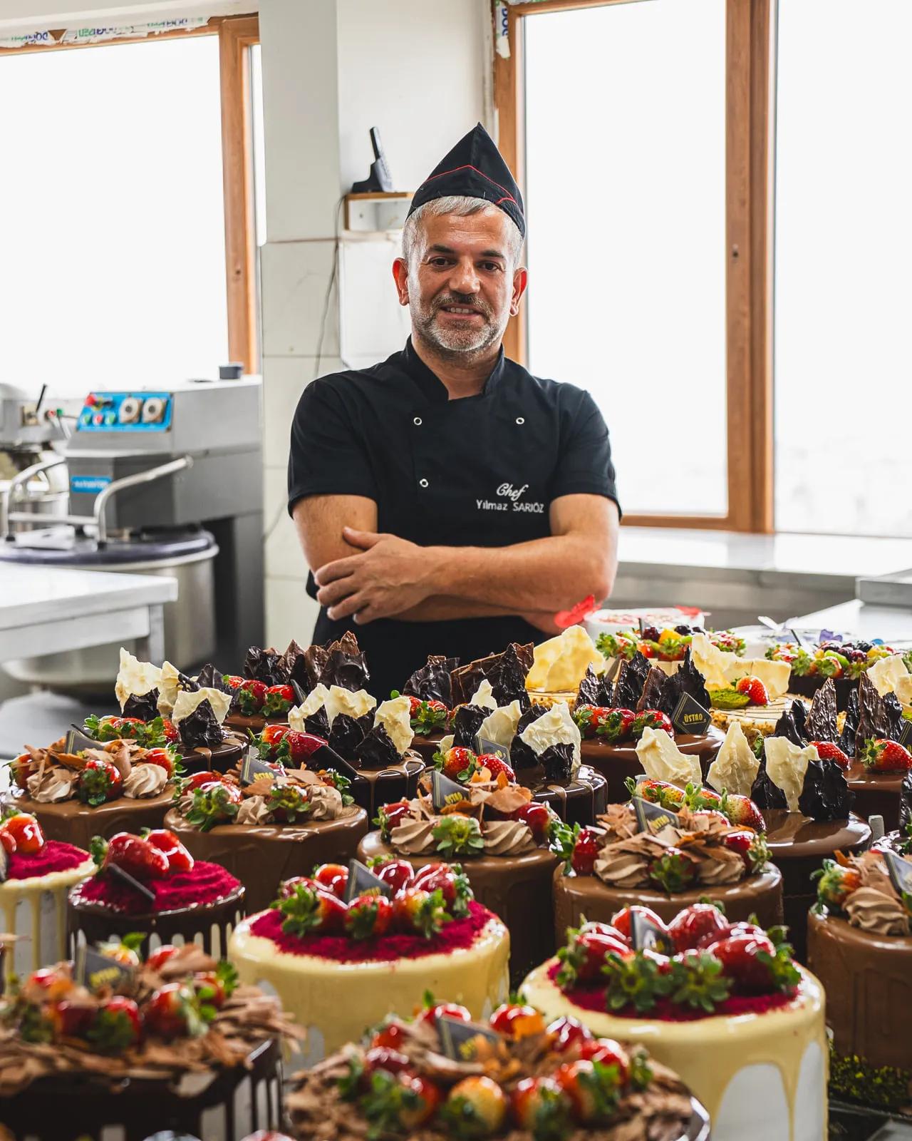 Üretimhanede, günün pastalarının önünde pasta ustası